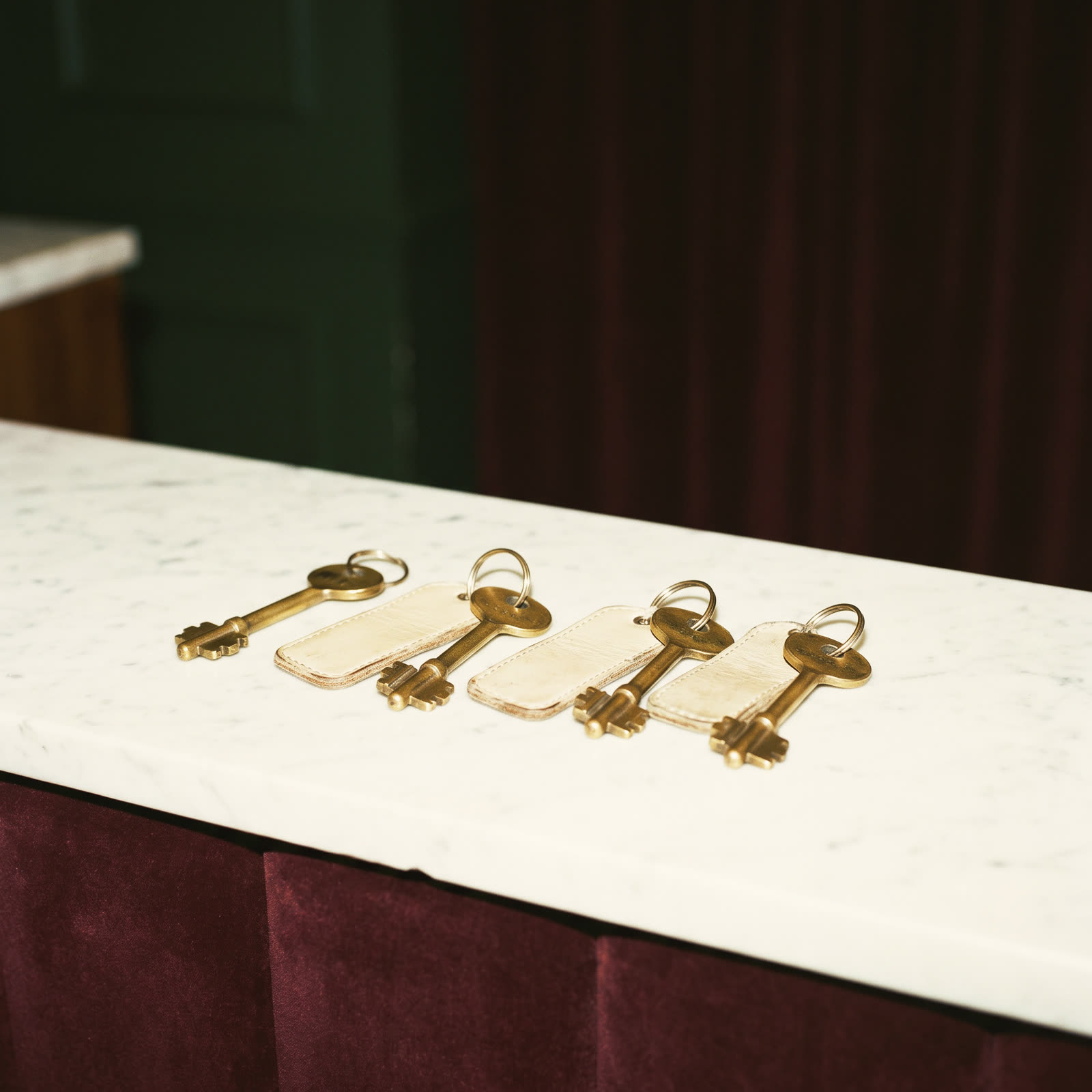 Four brass hotel keys with leather tags on a marble counter